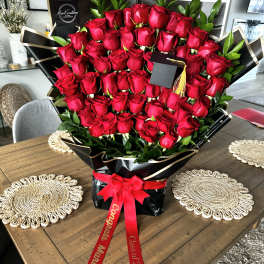 Large bouquet of red roses wrapped in black paper with a red ribbon