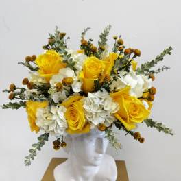 Yellow roses and white hydrangeas arranged in a white bust vase