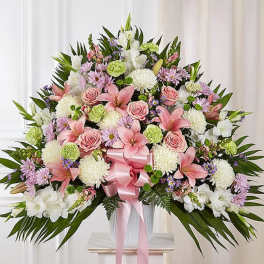 Large pink and white floral arrangement in a vase with a pink ribbon