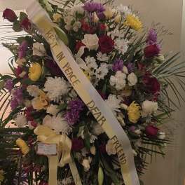 Large standing sympathy wreath with mixed flowers and a "Rest in Peace" ribbon
