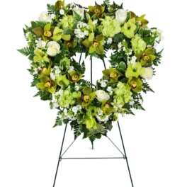 Heart-shaped floral wreath on a standing easel with green and white flowers