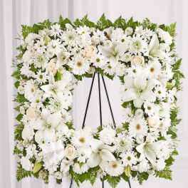White floral funeral wreath on a black easel