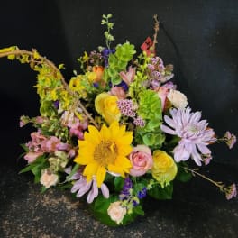 Colorful mixed flower arrangement with sunflowers, roses, and purple daisies