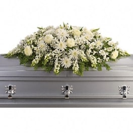 White floral casket spray on a silver casket