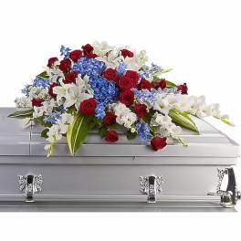Red, white, and blue casket spray with roses, lilies, and hydrangeas on a silver casket