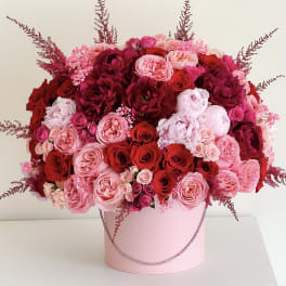 Large pink and red rose arrangement in a pink hatbox