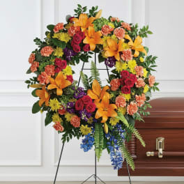 Colorful funeral wreath on an easel beside a casket