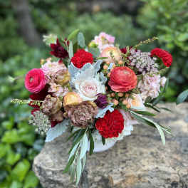 Mixed bouquet of pink, red, and white flowers in a low vase