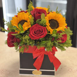 Red roses and sunflowers in a black box with a red ribbon