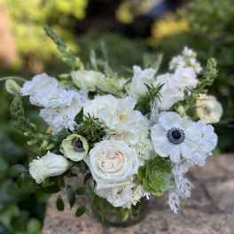 White floral bouquet in a glass vase with green accents