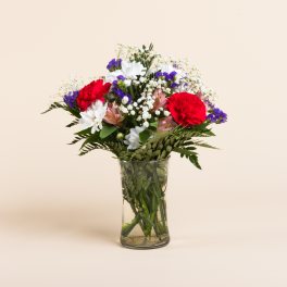Mixed bouquet of red, white, and purple flowers in a clear glass vase