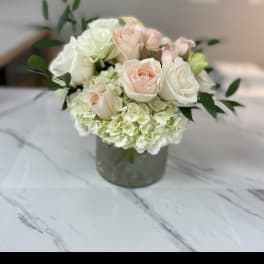 Blush and white roses arranged in a glass vase