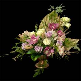Mixed bouquet with pink orchids, pale roses, and a decorative vase