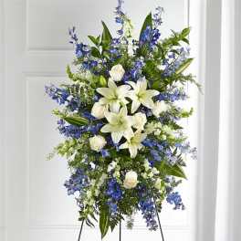 Tall standing spray of white lilies, roses, and blue flowers