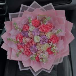 Pink bouquet of roses and carnations wrapped in layered pink paper