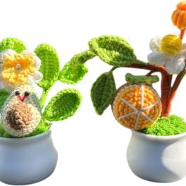 Two crocheted potted plants with flowers and fruit shapes