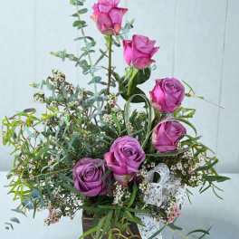 Purple roses in a wooden box with airy greenery and small white filler flowers