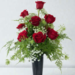 Red roses arranged in a black vase with airy white filler flowers