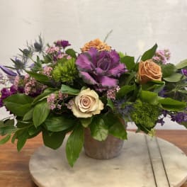 Mixed bouquet with roses, purple cabbage, and green thistle in a low vase