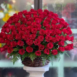 Large bouquet of red roses in a woven basket on a pedestal