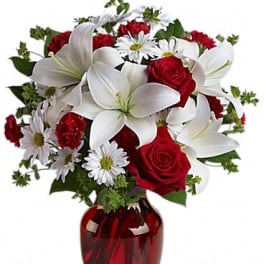 Bouquet of red roses and white lilies in a red glass vase
