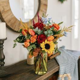 Mixed bouquet of roses and a sunflower in a glass vase