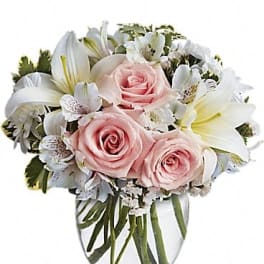 Pink roses and white lilies arranged in a clear glass vase