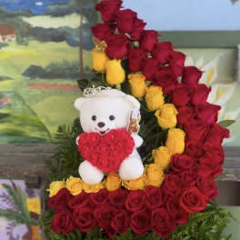 Red and yellow rose arrangement with a teddy bear holding a heart