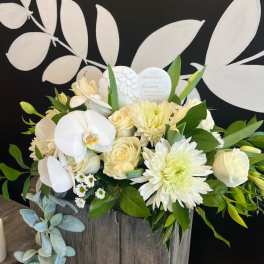 White floral arrangement in a rustic wooden box with orchids and roses