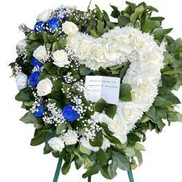Heart-shaped funeral wreath of white and blue roses on a stand