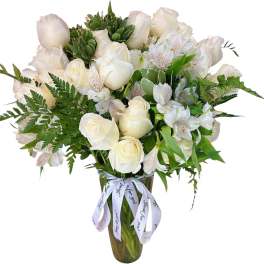 White roses and alstroemeria in a tall glass vase with a ribbon