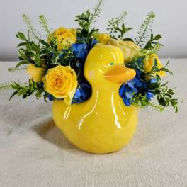 Yellow duck vase with yellow roses and blue flowers