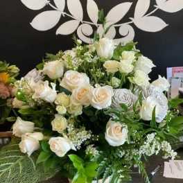 White rose arrangement with mixed greenery in a low container