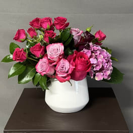 Pink and red roses with purple hydrangea in a white vase