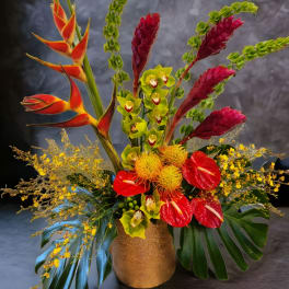 Tropical arrangement with red anthuriums, orchids, and heliconia in a gold vase