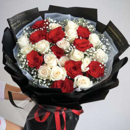 Bouquet of red and white roses wrapped in black paper with a red ribbon