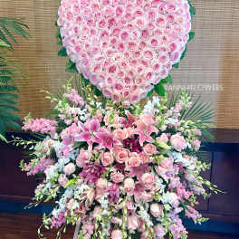 Heart-shaped pink rose arrangement above a cascading pink lily bouquet