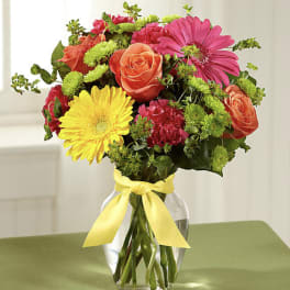 Mixed bouquet of roses, gerbera daisies, and carnations in a glass vase