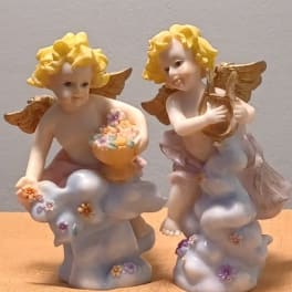 Two cherub figurines holding flower-filled bowls