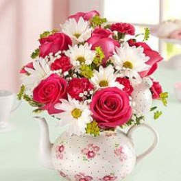 Pink roses and white daisies arranged in a floral teapot