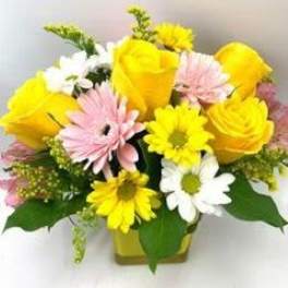 Yellow roses and pink, white, and yellow daisies in a vase