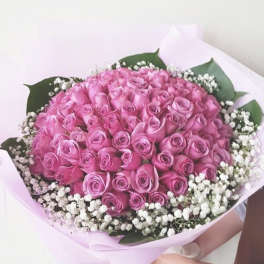 Large bouquet of pink roses with white baby's breath in pastel wrapping