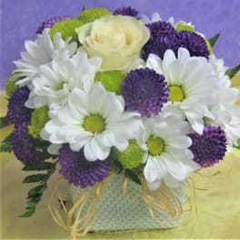 Bouquet of white daisies, purple blooms, and a pale yellow rose