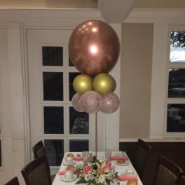 Table centerpiece with flowers and a tall balloon cluster above it