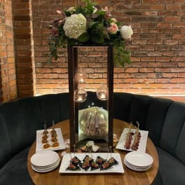 Floral centerpiece with white hydrangea and roses on a tall lantern stand