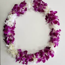 Purple and white orchid lei arranged in an oval shape on a plain light background