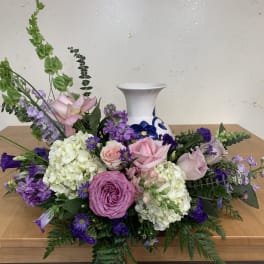 Low floral arrangement with pink and purple roses in a white vase