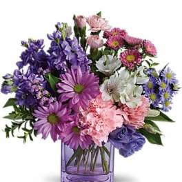 Mixed purple, pink, and white flowers in a purple glass vase