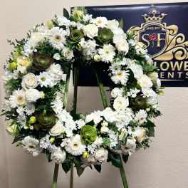 White floral wreath on a stand with roses and daisies
