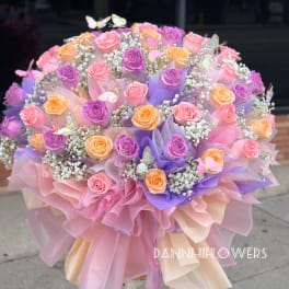Large bouquet of pink, purple, and peach roses with butterfly accents
